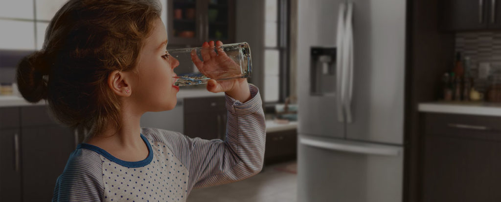 younger girl drinking a clear glass of water